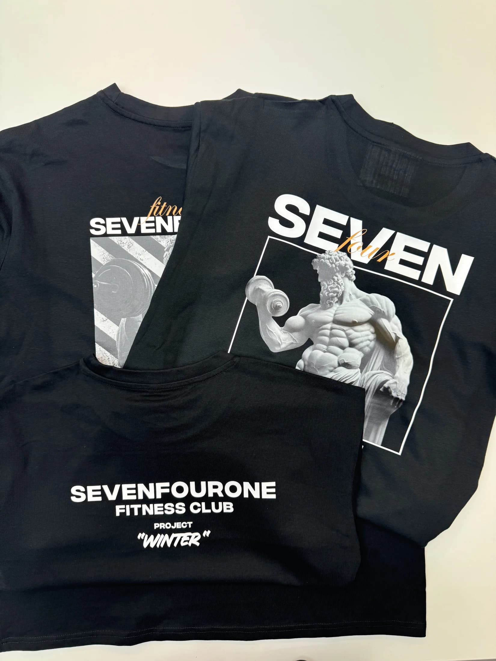 Drei schwarze Seven Four One Shirts mit unterschiedlichen Druckmotiven